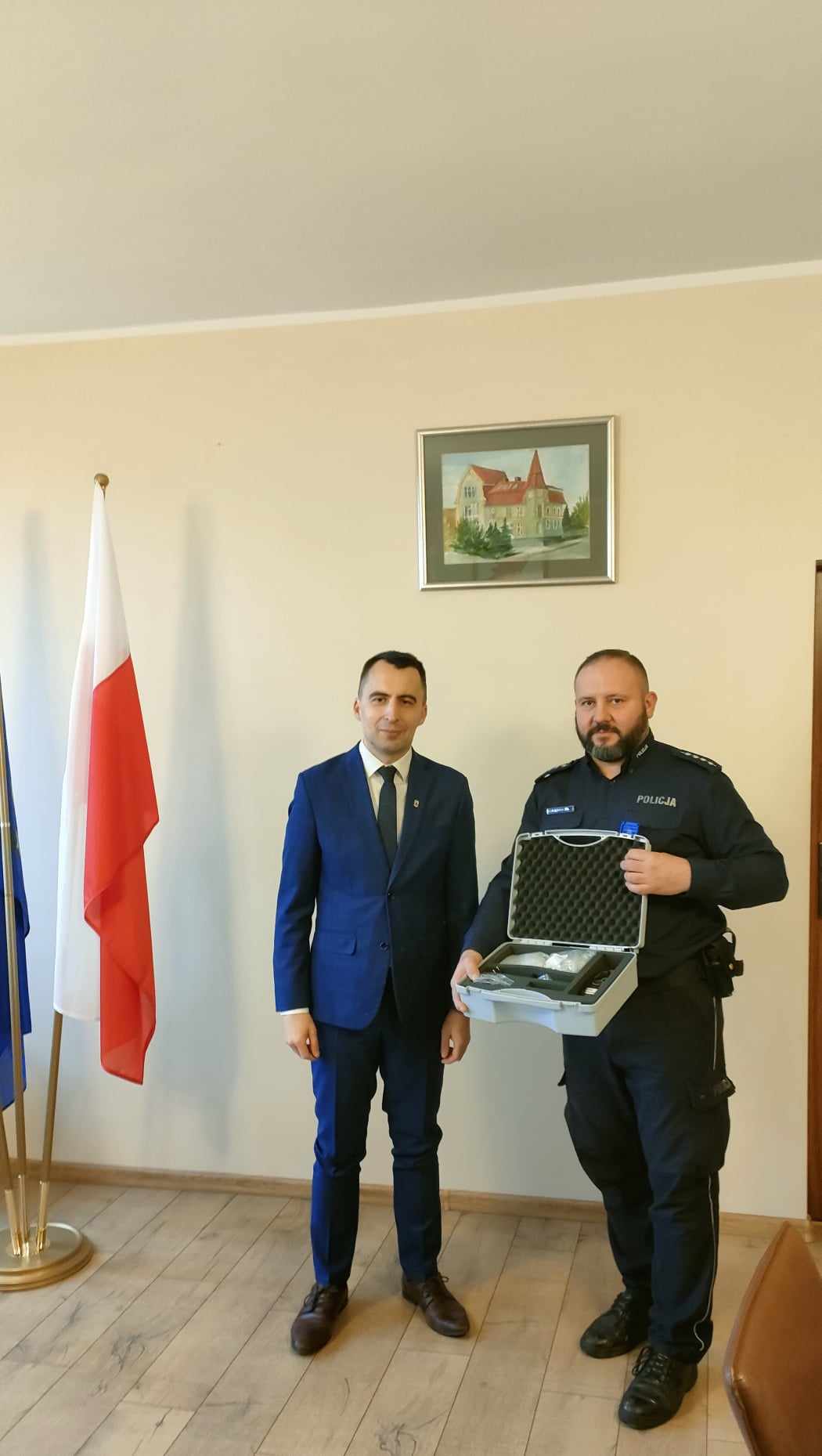 Burmistrz i&nbsp;Policjant trzymają walizkę, kt&oacute;rej jest nowy alkomat