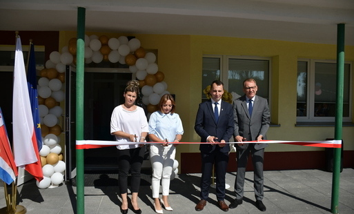 cztery osoby przecinają wstęgę przed wejściem do żłobka