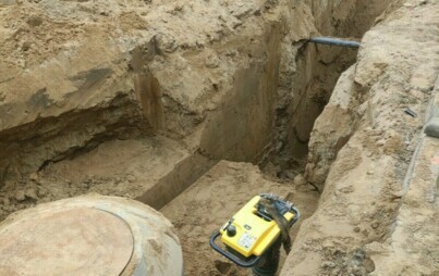 zdjęcie wykopanej dziury ze zbiornikiem do kanalizacji i maszyną do ubijania ziemi